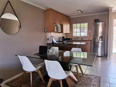 a kitchen with a glass table and white chairs at Lovely 2 Bedroom Townhouse with private garden in Centurion