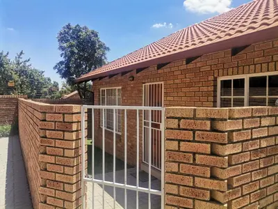 a brick fence with a gate in front of a house at Lovely 2 Bedroom Townhouse with private garden in Centurion