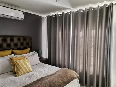 a bedroom with a bed and a window with curtains at Lovely 2 Bedroom Townhouse with private garden in Centurion