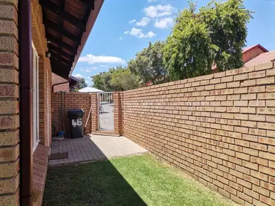 a brick wall with a gate in a yard at Lovely 2 Bedroom Townhouse with private garden in Centurion