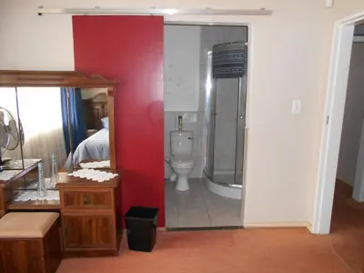 a bathroom with a toilet and a mirror at Pilot Inn Accommodation in Kempton Park