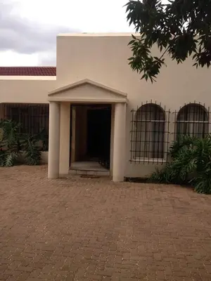 a white building with a door and a courtyard at Pilot Inn Accommodation in Kempton Park