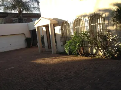 a fence in front of a house with palm trees at Pilot Inn Accommodation in Kempton Park