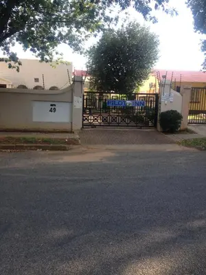 a gate to a building with a fence with graffiti at Pilot Inn Accommodation in Kempton Park