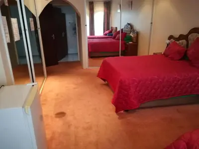 a bedroom with a red bed and a mirror at Pilot Inn Accommodation in Kempton Park