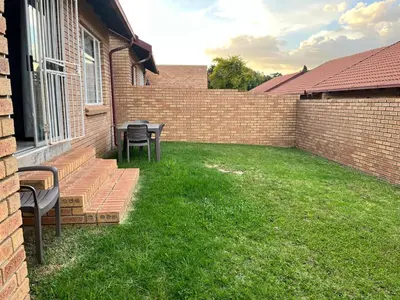 a patio with two chairs and a table in a yard at The Reeds Private Garden House in Centurion