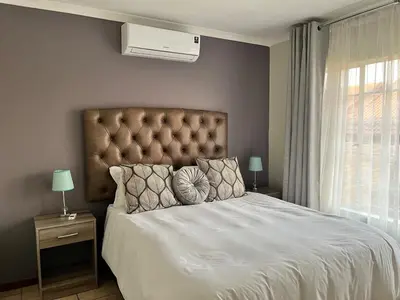 a bedroom with a large white bed with a large window at The Reeds Private Garden House in Centurion