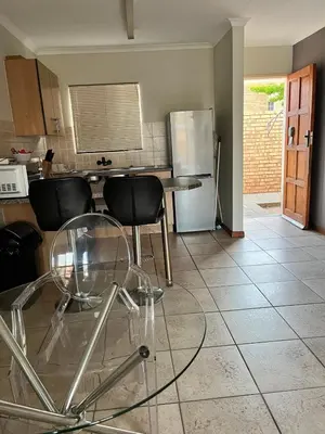 a kitchen with a table and chairs and a refrigerator at The Reeds Private Garden House in Centurion