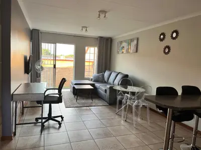 a living room with a couch and a table and chairs at The Reeds Private Garden House in Centurion