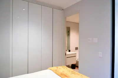a bedroom with white walls and a bed and a sink at Luxury Escape at Ellipse 1-Bed, Kitchen, Wi-Fi & Free Parking in Midrand
