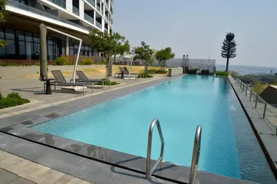 a large blue swimming pool in front of a building at Luxury Escape at Ellipse 1-Bed, Kitchen, Wi-Fi & Free Parking in Midrand