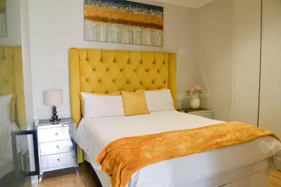 a bedroom with a large bed with a yellow headboard at Luxury Escape at Ellipse 1-Bed, Kitchen, Wi-Fi & Free Parking in Midrand