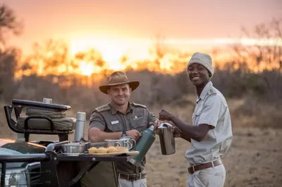 two men standing next to a picnic table with a grill at Karongwe - Kuname Safari Lodge in Hoedspruit