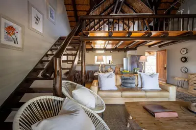 a living room with a staircase with wicker chairs at Karongwe - Kuname Safari Lodge in Hoedspruit