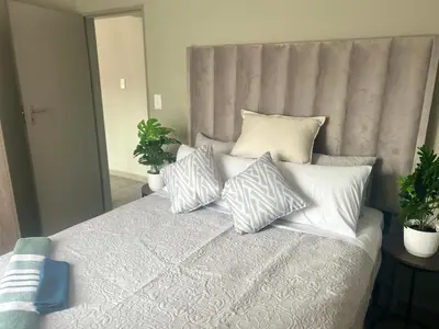 a bedroom with a bed with pillows on it at Cosy Apartment in Pretoria