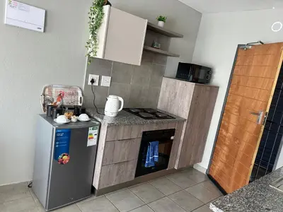 a small kitchen with a refrigerator and an oven at Cosy Apartment in Pretoria