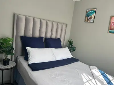 a bed with blue and white pillows on it at Cosy Apartment in Pretoria