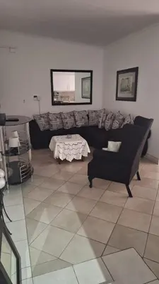 a living room with a black couch and a table at Casa Maya in Pretoria