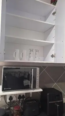 a microwave on a shelf in a kitchen at Casa Maya in Pretoria