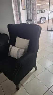 a black chair with a pillow on a tile floor at Casa Maya in Pretoria