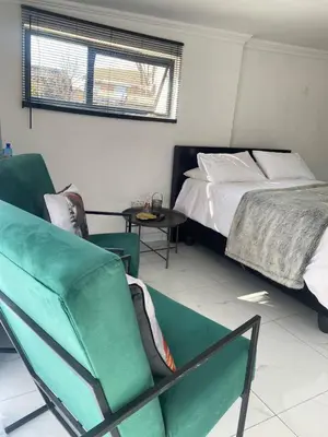 a bedroom with a bed and a couch and a chair at Lakeside Studio Sleeps max 2 in Benoni