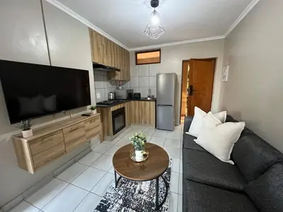 a living room with a couch and a tv and a table at Apartment with stunning scenic views in Pretoria