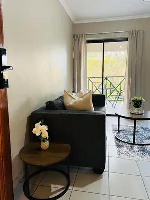 a living room with a black couch and two tables at Apartment with stunning scenic views in Pretoria