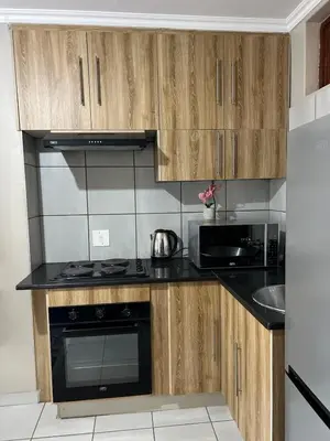 a kitchen with wooden cabinets and a stove top oven at Apartment with stunning scenic views in Pretoria
