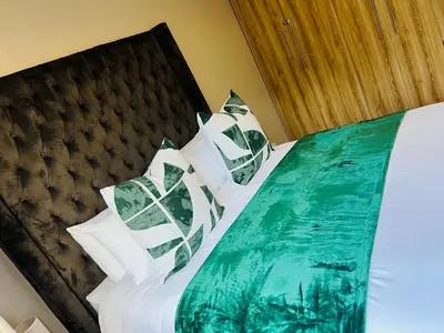 a bed with white and green sheets and pillows at Apartment with stunning scenic views in Pretoria
