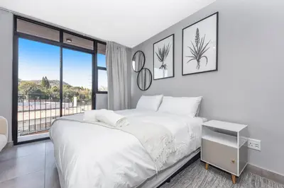a bedroom with a white bed and a large window at Circa Lynwood Accommodation in Pretoria