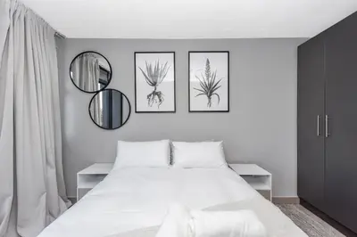 a bedroom with a white bed and three mirrors at Circa Lynwood Accommodation in Pretoria