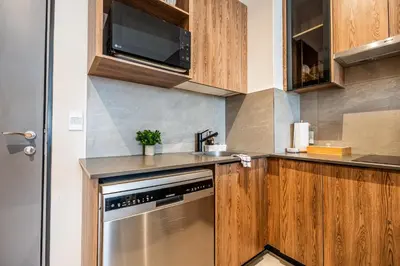a kitchen with wooden cabinets and a stainless steel dishwasher at Menlyn Luxury Studio KingBed XL Free Parking 137 in Pretoria