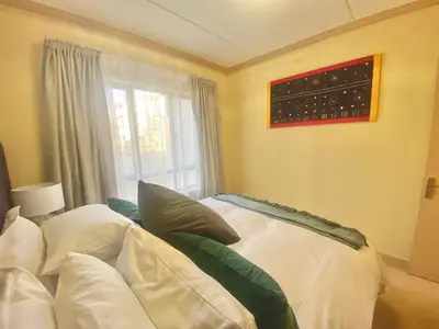 a room with a bed with pillows and a window at Phoenix Rising Apartment in Midrand