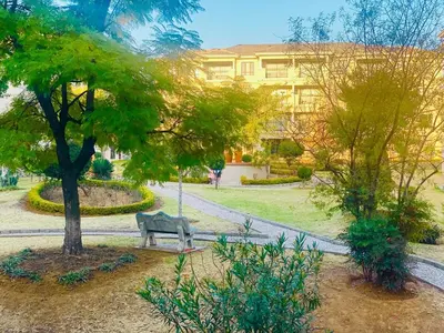 a park with a bench and a tree and a building at Phoenix Rising Apartment in Midrand