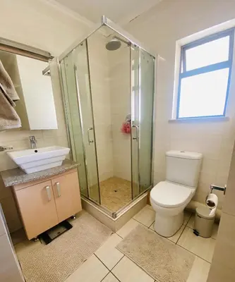 a bathroom with a shower and a toilet and a sink at Phoenix Rising Apartment in Midrand