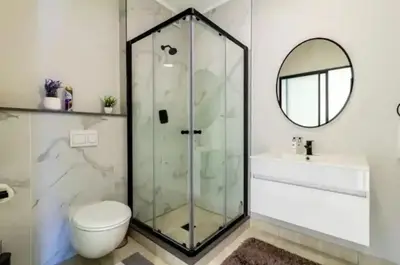 a bathroom with a shower and a toilet and a mirror at #AlimamaSpaces The Rob's Polofields in Midrand