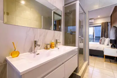 a bathroom with a sink and a mirror and a bed at AlimamaSpacesThe Mansons Cascades Villa in Midrand