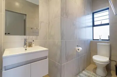 a bathroom with a toilet and a sink and a mirror at AlimamaSpacesThe Mansons Cascades Villa in Midrand