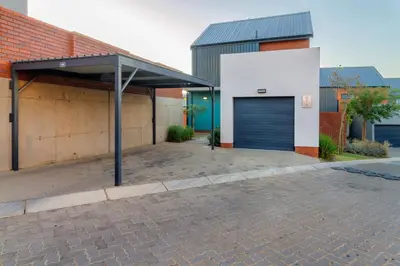 a garage with a blue door and a brick building at AlimamaSpacesThe Mansons Cascades Villa in Midrand