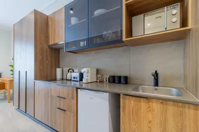 a kitchen with a sink and wooden cabinets at AlimamaSpaces The Noxy Menlyn Maine in Pretoria