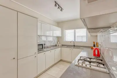 a kitchen with white cabinets and a red appliance at AlimamaSpaces Semandi Polofields in Midrand