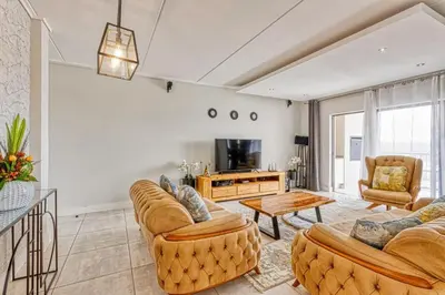a living room with two couches and a tv at AlimamaSpaces Semandi Polofields in Midrand