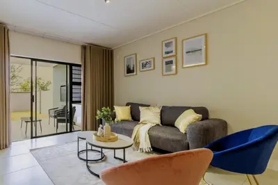 a living room with a couch and a table and chairs at AlimamaSpaces Josephs Polofields in Midrand