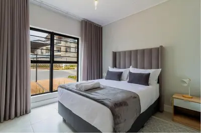 a bedroom with a large bed and a large window at AlimamaSpaces Josephs Polofields in Midrand