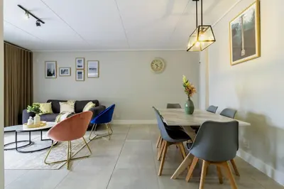 a dining room with a table and chairs and a couch at AlimamaSpaces Josephs Polofields in Midrand