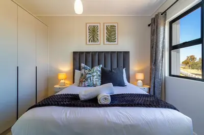 a bedroom with a large bed with a window at AlimamaSpaces Panos Whisken in Midrand