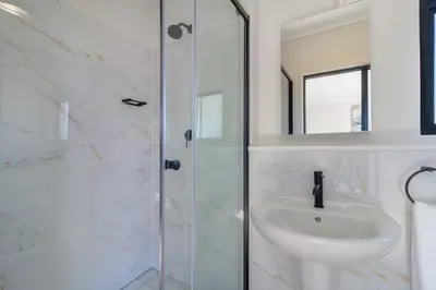 a white bathroom with a sink and a shower at AlimamaSpaces Panos Whisken in Midrand