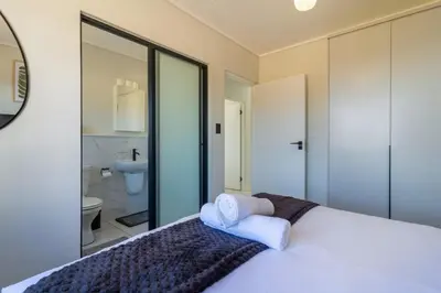 a bedroom with a white bed and a bathroom at AlimamaSpaces Panos Whisken in Midrand