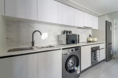 a white kitchen with a washing machine and a sink at AlimamaSpaces Phillys Whisken in Midrand