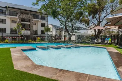a large swimming pool in a yard with a building at AlimamaSpaces Phillys Whisken in Midrand